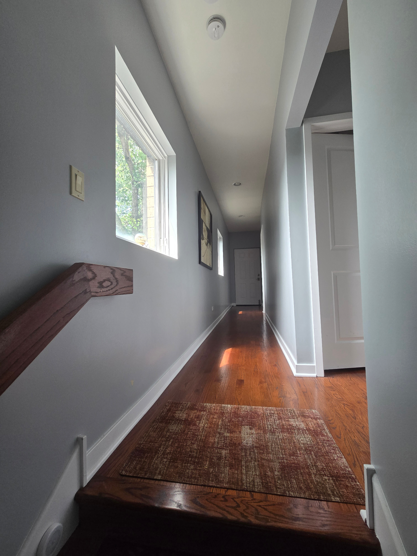 Upper-floor hallway with vaulted ceiling, hardwood floors, and natural light