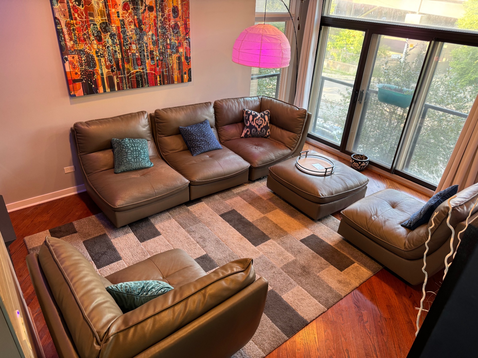 Living room sectional seating with abstract art and floor-to-ceiling windows