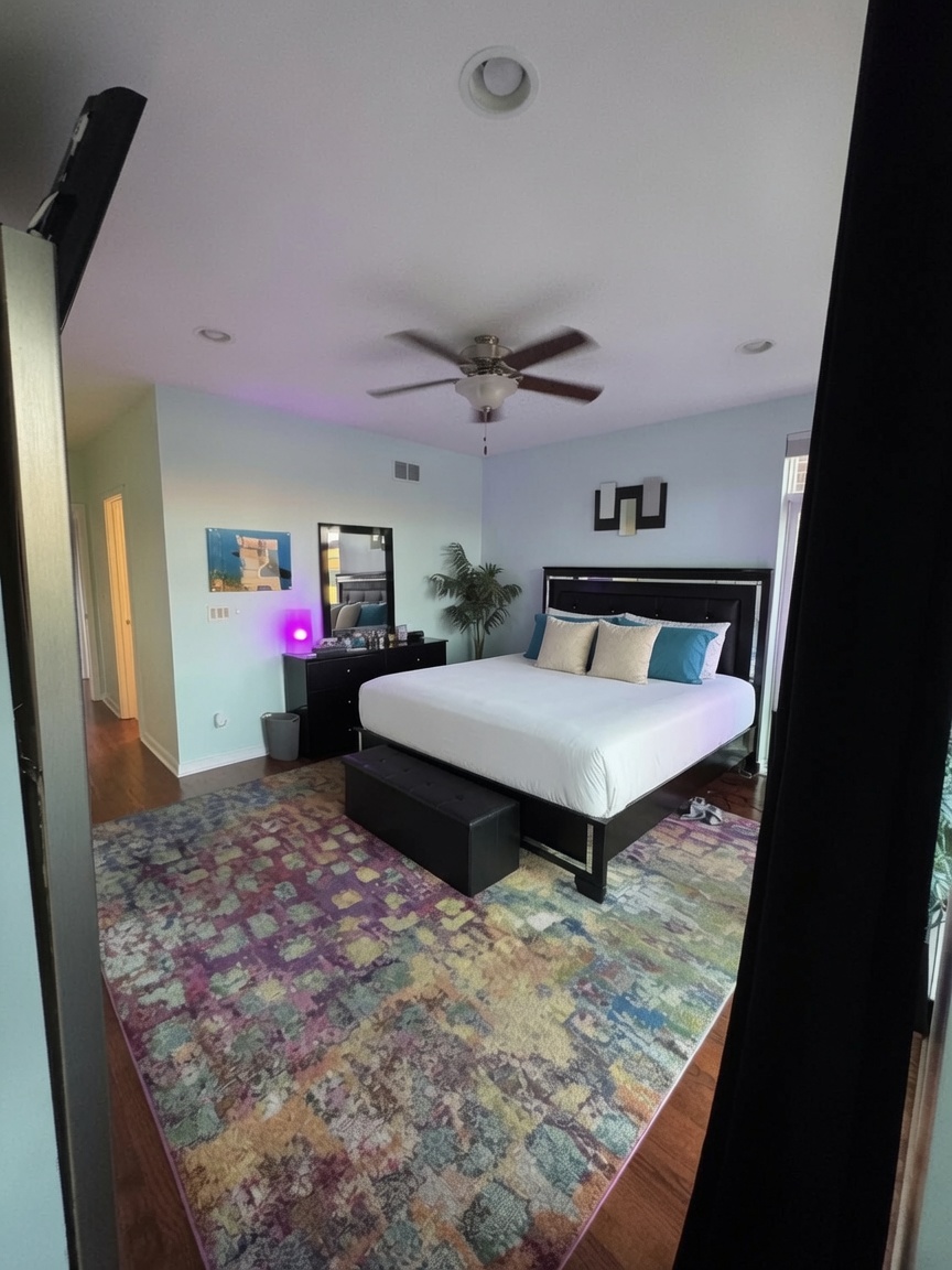 Primary bedroom with king bed, ceiling fan, and colorful area rug